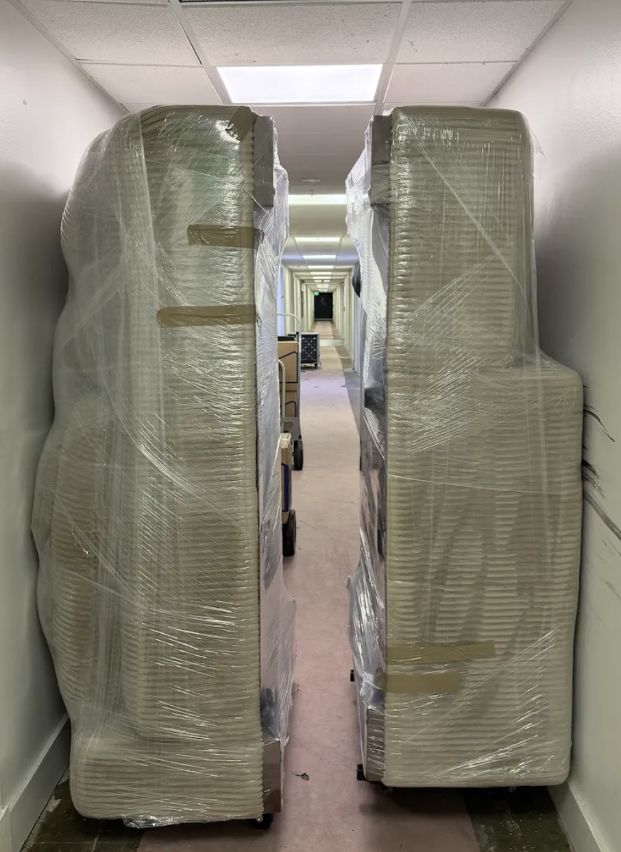 Wrapped mattresses carefully navigated through a narrow hallway
