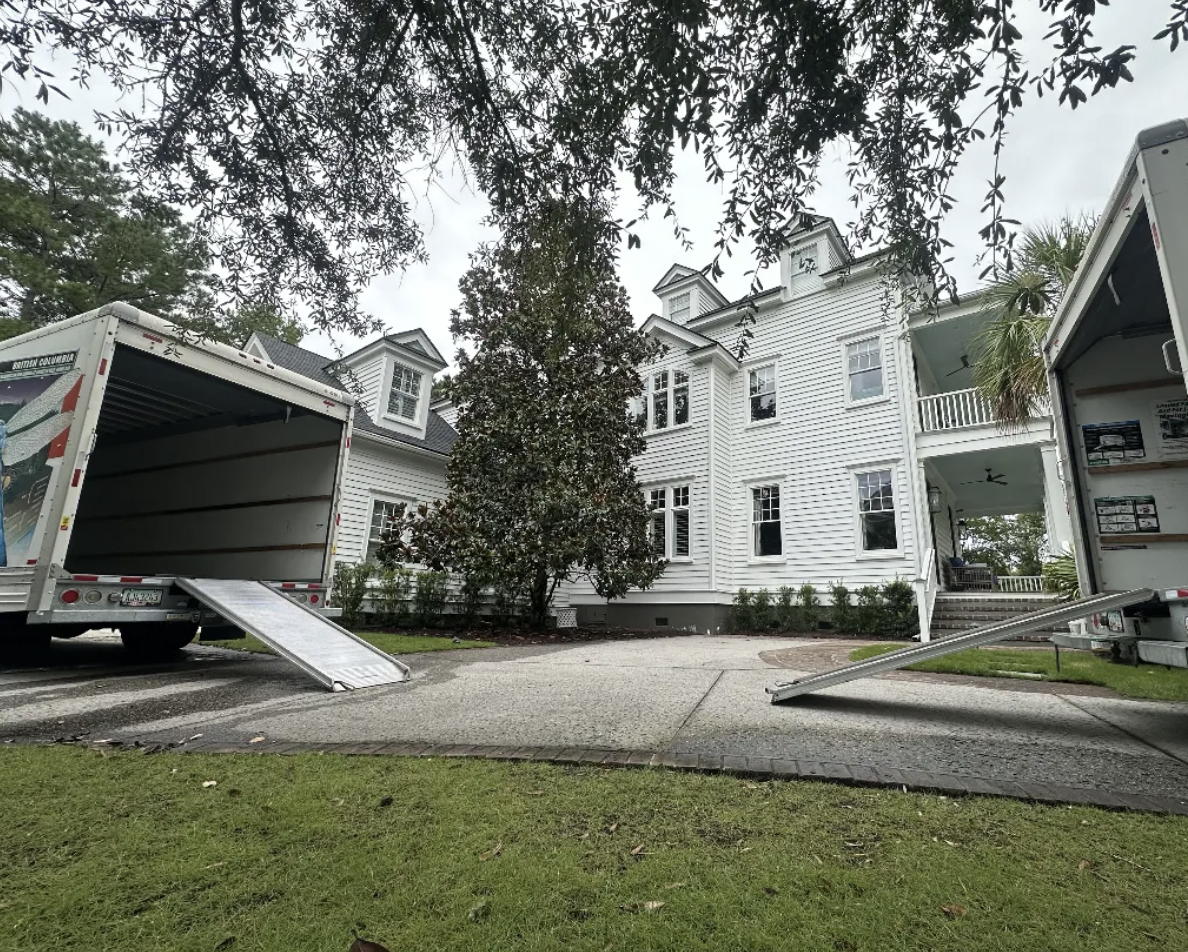 Two trucks staged with ramps down at a large estate